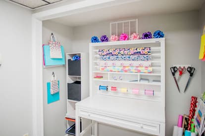 White gift wrapping station with bags, bows and wrapping paper of all colors. 